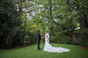 千里阪急ホテルにてガーデンで木々の囲まれながら手を合わせて向かい合う新郎新婦