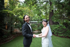 千里阪急ホテルにて木々を背景に手を合わせる新郎新婦
