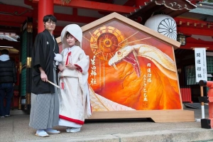 生田神社にて大絵馬の前に立つ新郎新婦