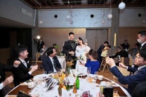 THE SORAKUENにてテーブルのゲストに笑顔を送る新郎新婦
