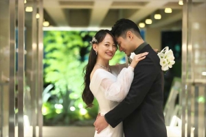 THE SORAKUENにてカメラに目線を送り新婦と新婦を軽く抱きしめる新郎