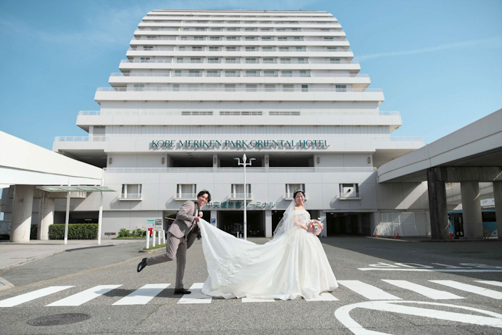 神戸メリケンパークオリエンタルホテルで新郎が新婦のドレスの裾を持って写真を写真撮影