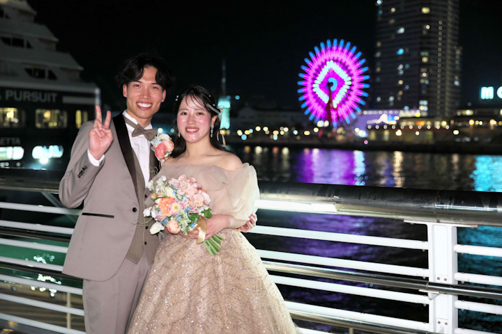 神戸メリケンパークオリエンタルホテルで夜景をバックにピースで写真を撮る新郎新婦