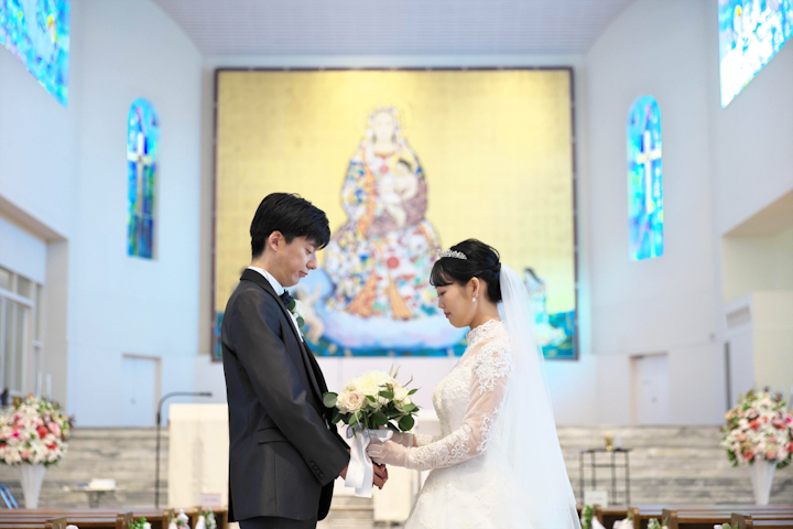 カトリック玉造教会にてブーケを見つめて向かい合う新郎新婦