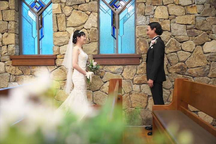 千里阪急ホテルにてチャペルで向かい合ってほほ笑む新郎新婦