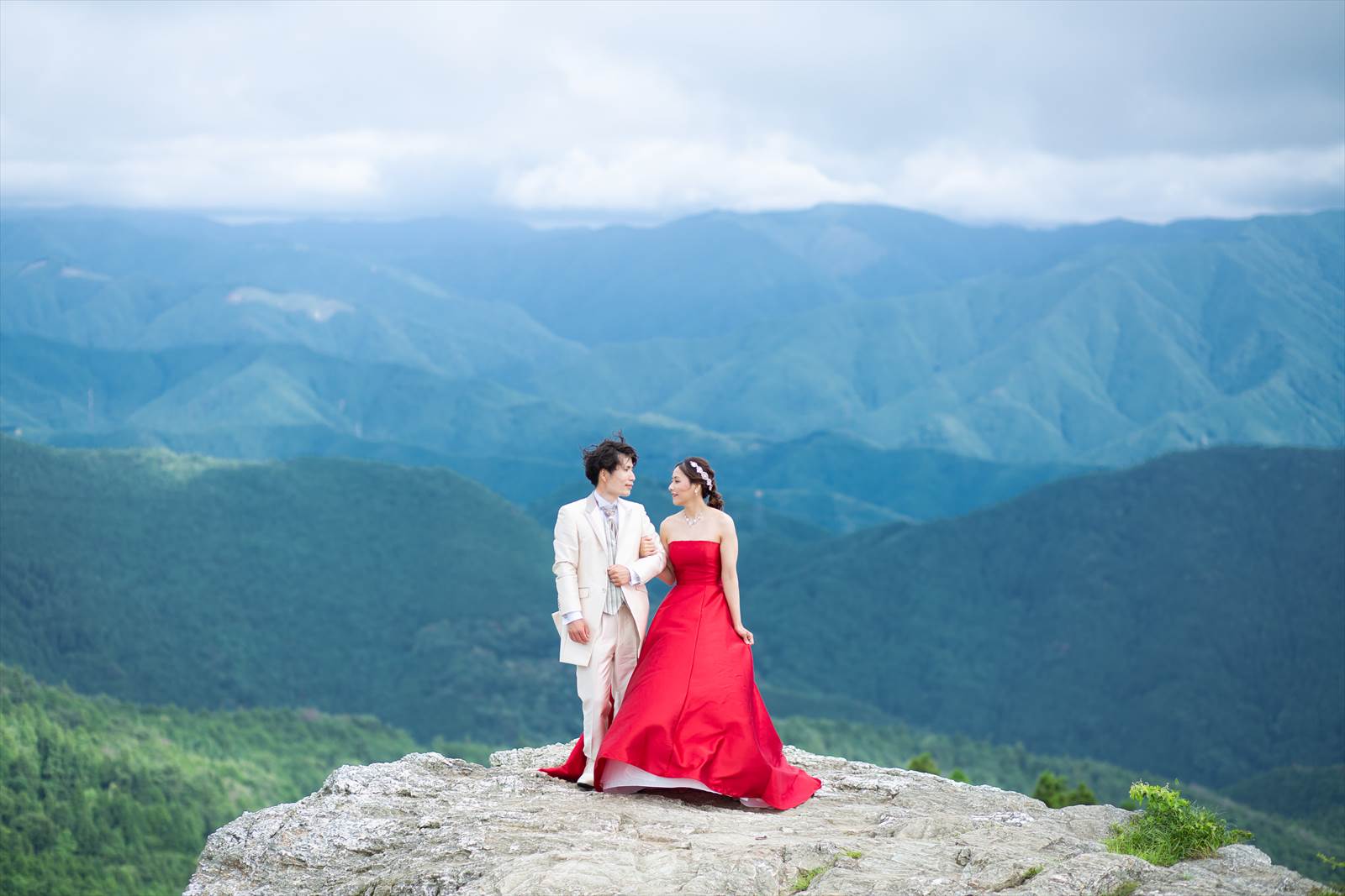 結婚式カメラマンが撮影：生石高原の崖の上に立つ新郎新婦の洋装での前撮り写真
